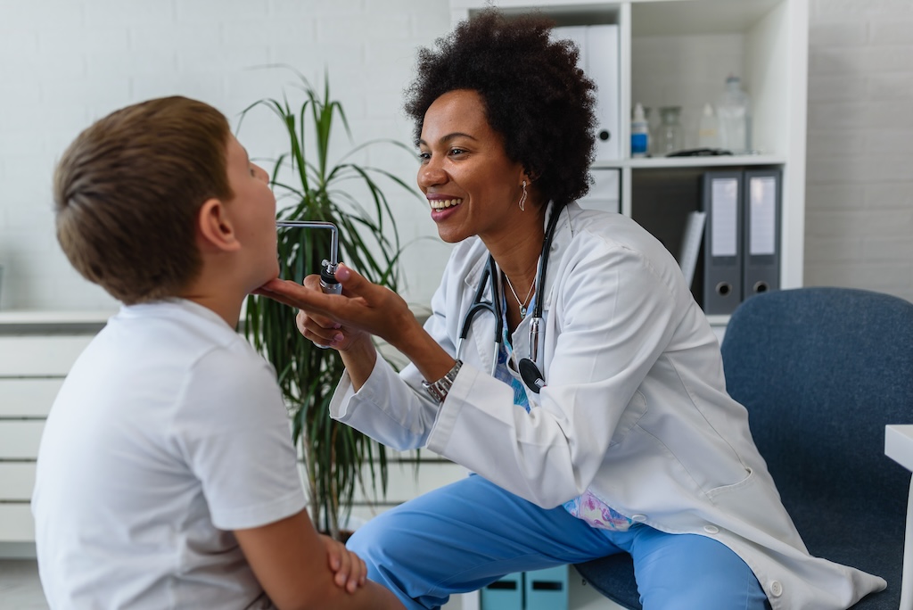 Woman doctor general practitioner examining child’s sore throat